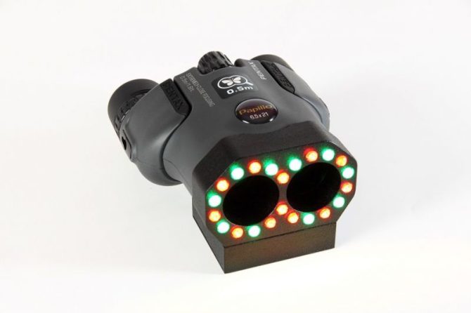 The Optic-2 hidden camera detector in action, highlighting camera lenses with yellow light in an office space.